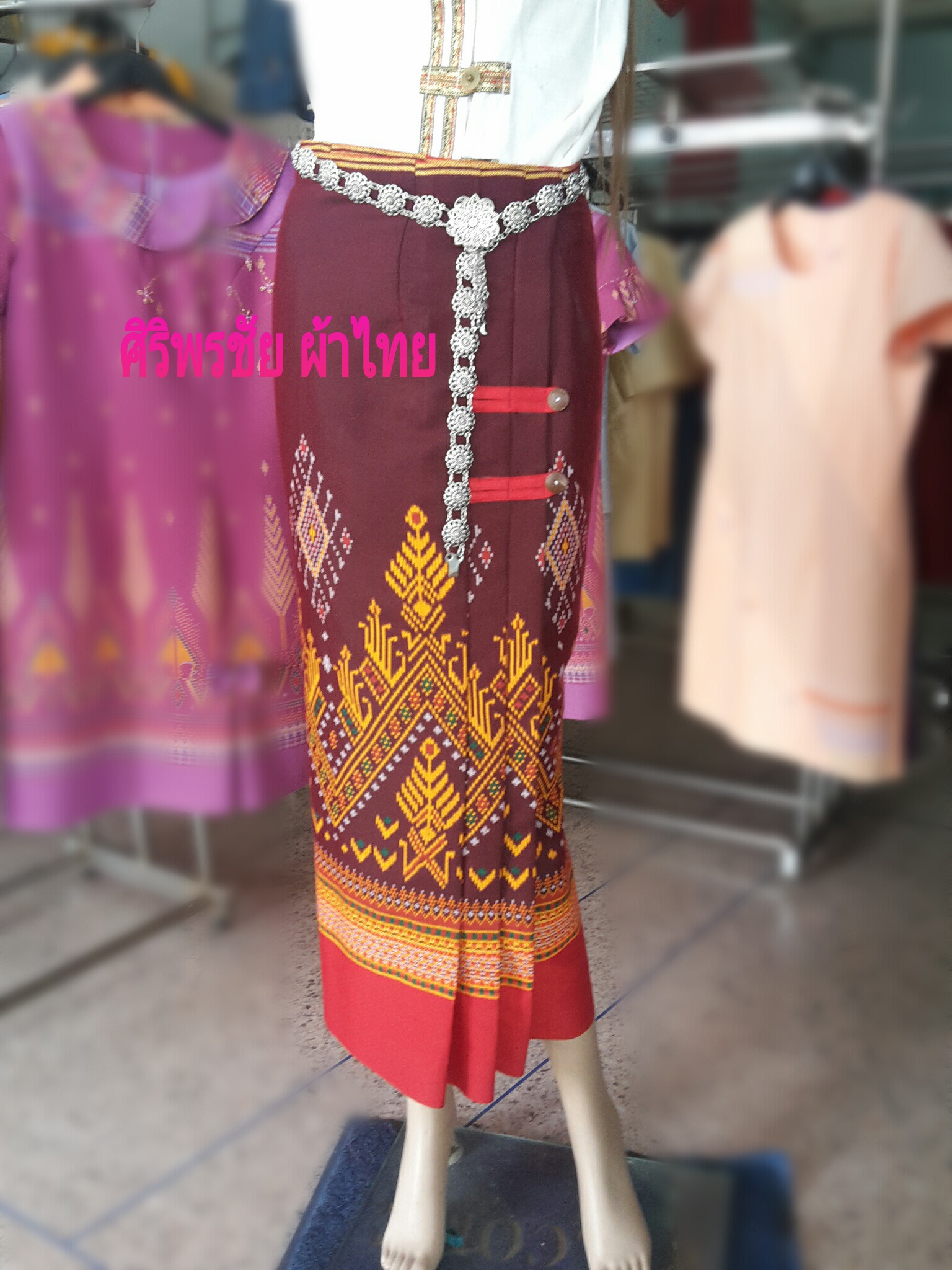 ผ้าซิ่นสำเร็จรูปผ้าซิ่นผ้าฝ้าย แบบป้ายแต่งจีบกระดุมปั้มลายพนมอัปศราฉัตร ผ้าซิ่นตัดสำเร็จพื้นม่วงตีนแดง